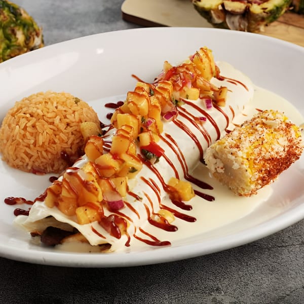 El Patron Mexican Grill's burrito with pineapple salsa, white sauce, rice, and elote on a white plate.